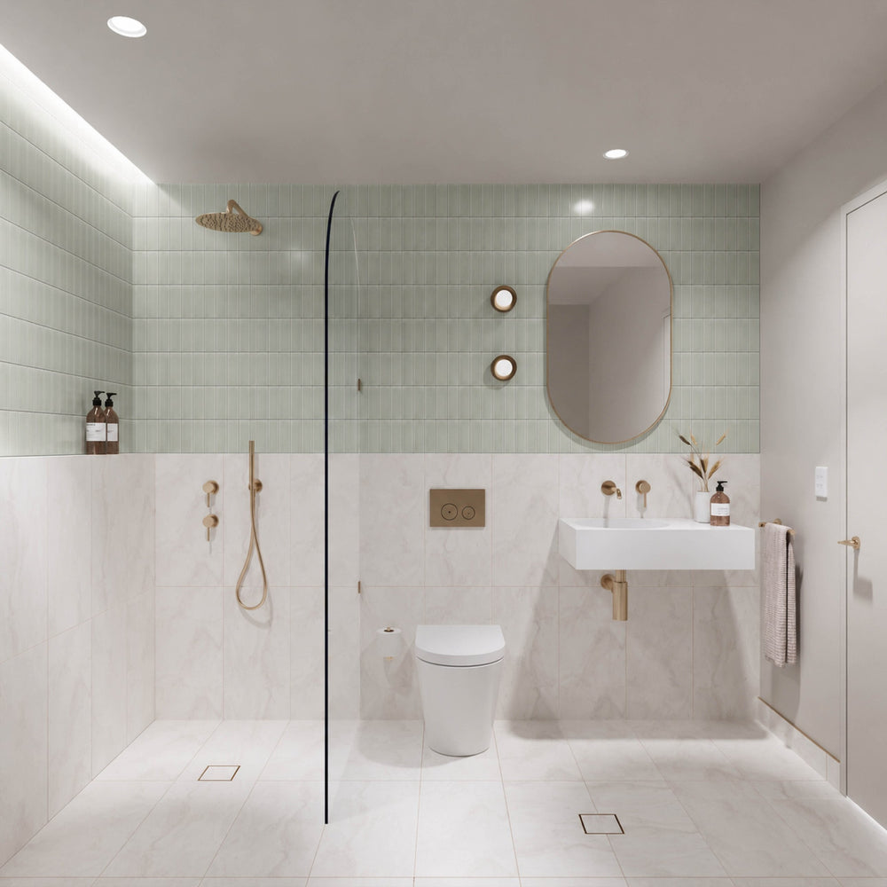 Sage green and white marble-look tiled bathroom with walk-in shower, white wall-hung basin, pill-shaped mirror and gold fittings
