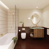 Burgundy tiled bathroom with shower over bath, timber vanity, green stone benchtop, pebble-shaped mirror and gold fittings