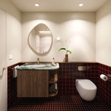 Square burgundy tiled bathroom with timber vanity, green stone benchtop, pebble-shaped mirror and wall-hung toilet