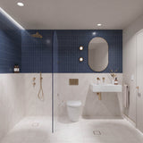 Navy and white marble-look tiled bathroom with walk-in shower, white wall-hung basin, pill-shaped mirror and gold fittings