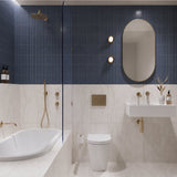 Navy and white marble-look tiled bathroom with shower over bath, white wall-hung basin, pill-shaped mirror and gold fittings