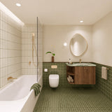 Olive green tiled bathroom with shower over bath, timber vanity, green stone benchtop, pebble-shaped mirror and gold fittings