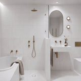 Long white tiled bathroom with marble-look tiles, tiled-in bath, walk-in shower and white wall-hung basin