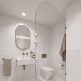 Square white tiled bathroom with marble-look tiles, arched glass shower screen, white wall-hung basin and pill-shaped mirror