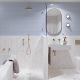 Long light blue and white marble-look tiled bathroom with tiled-in bath, walk-in shower and white wall-hung basin