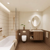 Terracotta tiled bathroom with shower over bath, timber vanity, cream stone benchtop, pebble-shaped mirror and gold fittings