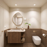 Square terracotta tiled bathroom with timber vanity, cream stone benchtop, pebble-shaped mirror and wall-hung toilet