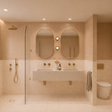 Large peach and cream marble-look tiled bathroom with double white basin, two pill-shaped mirrors and walk-in shower